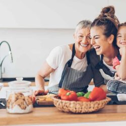 Three generations women laughing in the kitchen Three-generation women - grandmother, mother and small girl having fun in the kitchen, with copy space.